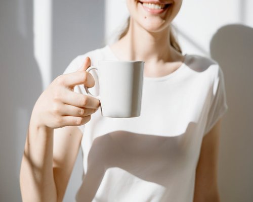Smiling relaxed person enjoying a morning cup of tea or coffee outside